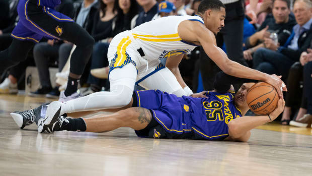 Warriors guard Jordan Poole and Lakers forward Juan Toscano-Anderson fight for the ball.